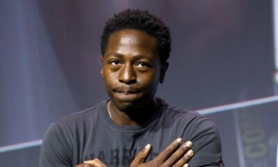 David Jonsson crossing his arms over his chest in the Wakanda Forever salute while holding a microphone on stage at San Diego Comic-Con 2026.