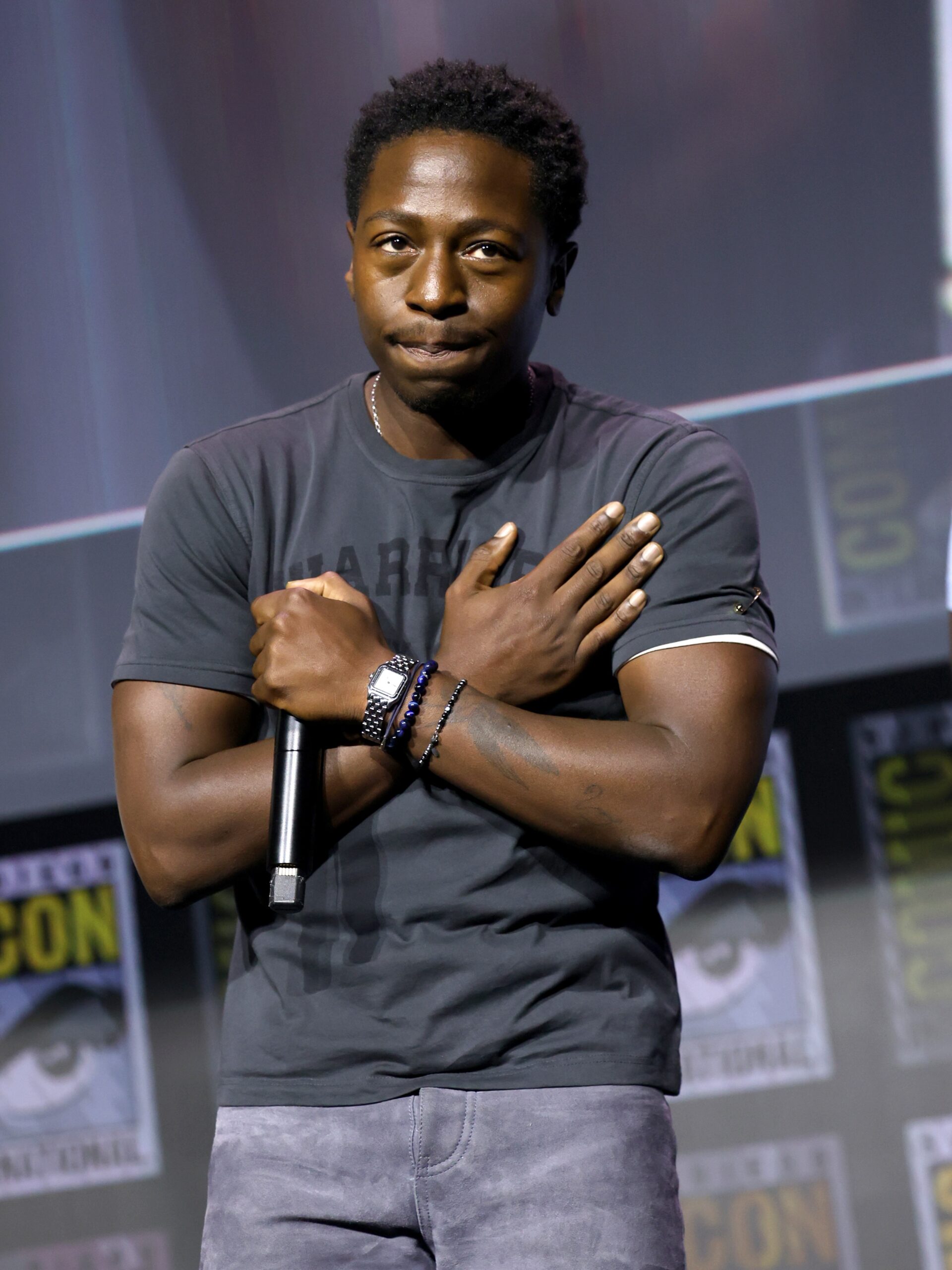 David Jonsson crossing his arms over his chest in the Wakanda Forever salute while holding a microphone on stage at San Diego Comic-Con 2026.