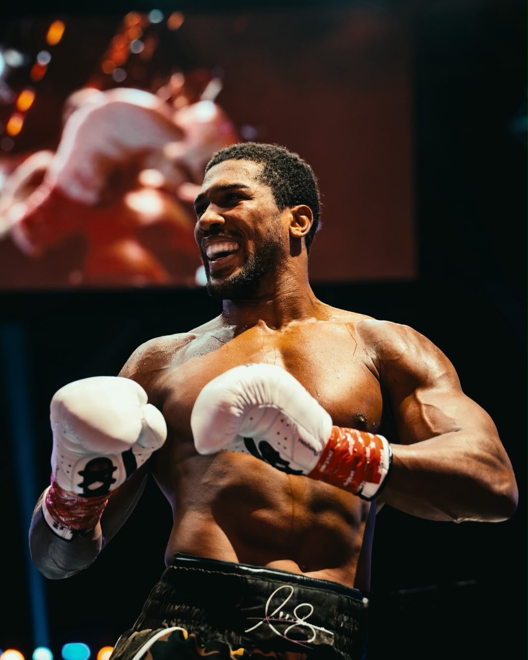Anthony Joshua smiling in white Everlast boxing gloves inside the ring after his second-round knockout victory over Kristian Prenga at the Jeddah Superdome.