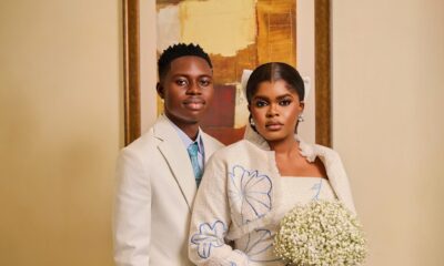 Studio portrait of Peller and Jarvis in off-white wedding outfits with blue floral embroidery.