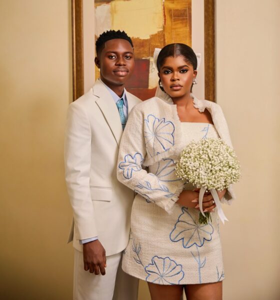 Studio portrait of Peller and Jarvis in off-white wedding outfits with blue floral embroidery.