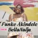 Funke Akindele smiling during her exclusive BellaNaija interview, wearing a floral mini dress and gold jewellery, seated against a colourful abstract painting backdrop