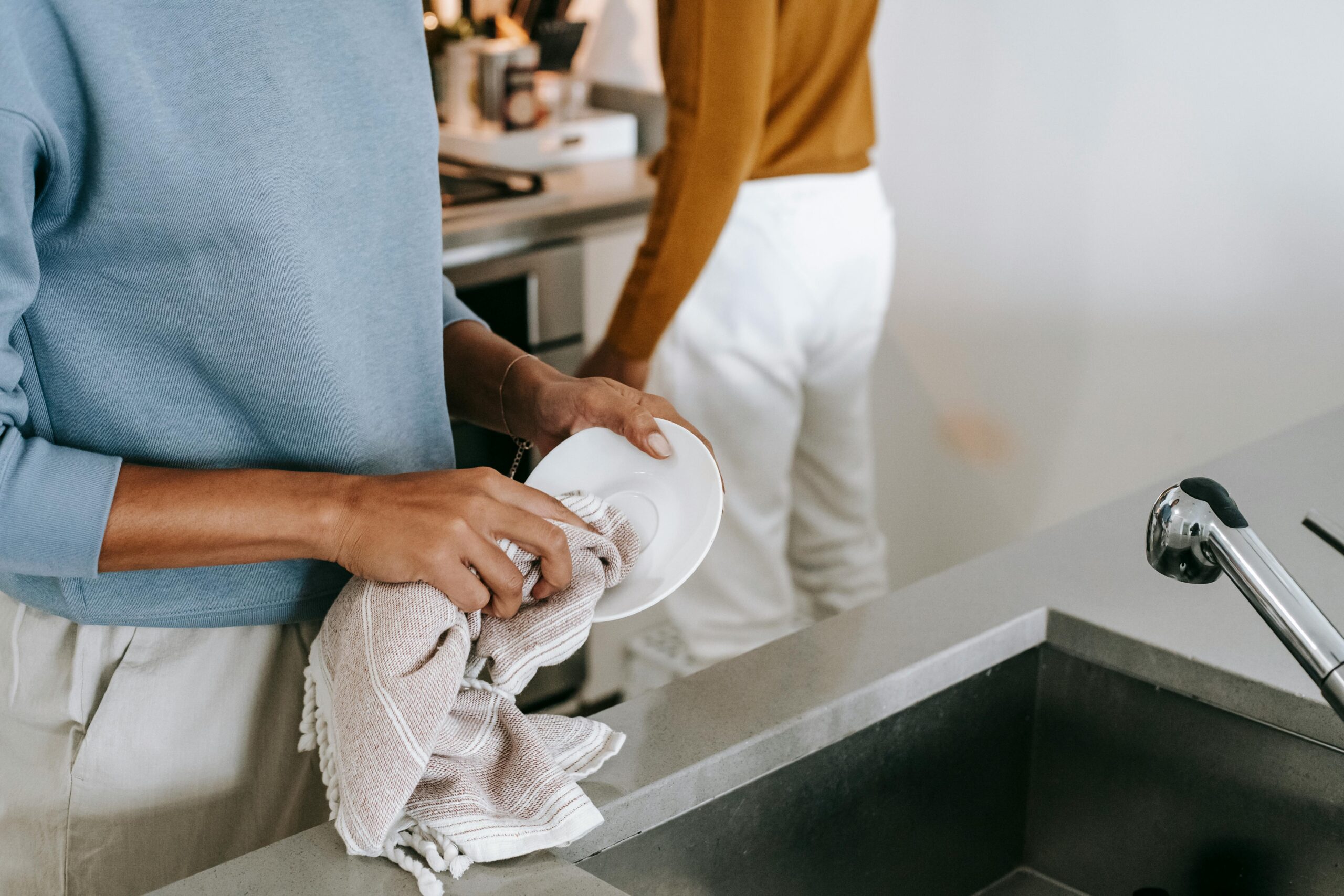 Young couple bonding over kitchen chores, emphasizing modern lifestyle and relationship. Photo credit: Alex Green/Pexels.