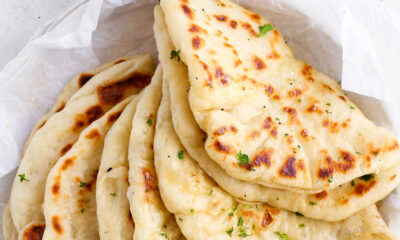 Freshly baked homemade skillet naan brushed with melted garlic butter and chopped parsley in a parchment-lined basket.