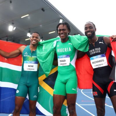 Samuel Ogazi celebrating with Nigerian flag alongside Zakithi Nene of South Africa and Jereem Richards of Trinidad and Tobago after winning men's 400m gold at Glasgow 2026 Commonwealth Games.