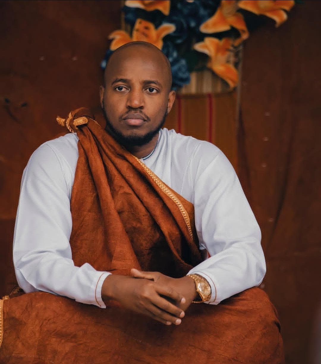 King Oyo Nyimba Kabamba Iguru Rukidi IV wearing a traditional brown barkcloth shoulder drape over a white garment.