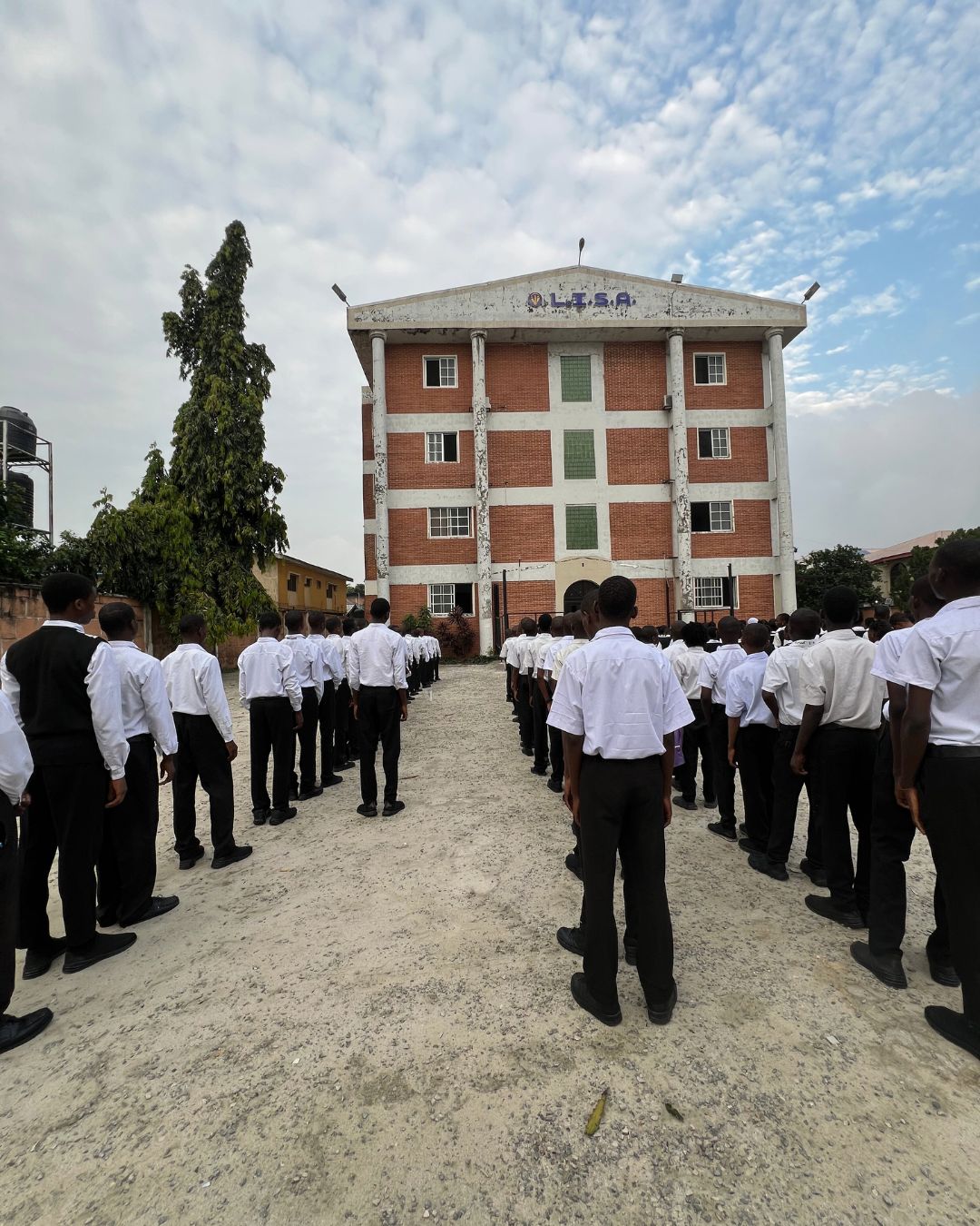 Students at Let It Shine Academy lined up in white uniforms during morning assembly in front of the four-story L.I.S.A. campus building.