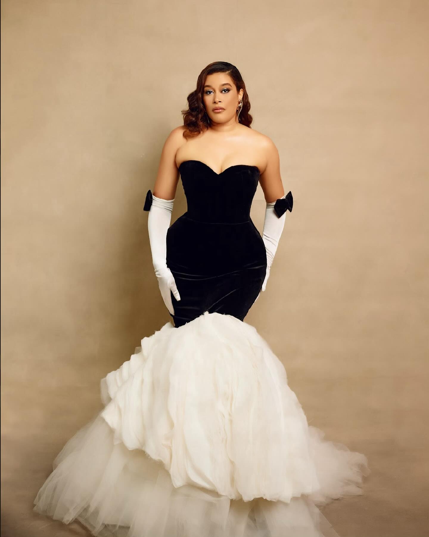 Adunni Ade wearing a black and white Ann Cranberry corset gown with white opera gloves at the 10th AMVCA red carpet.