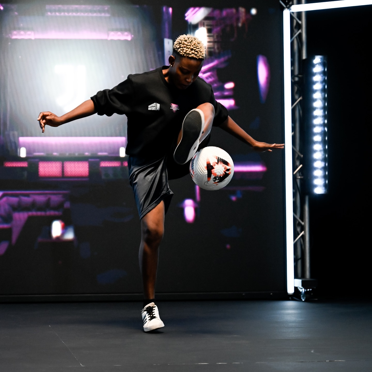 Evelyn Okafor balancing a football on her foot during a live freestyle performance