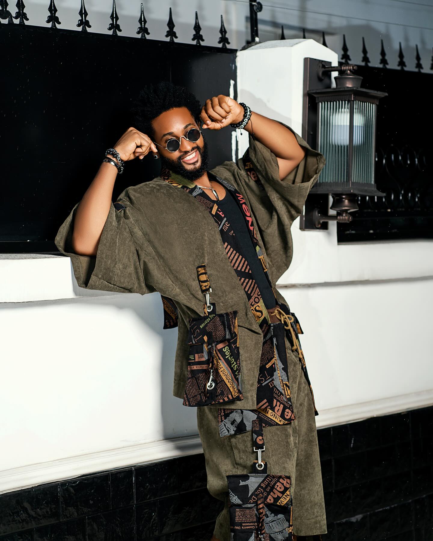 BBNaija Season 11 housemate Chimsom Chuka posing in an olive green kimono set with newspaper print details and round sunglasses.