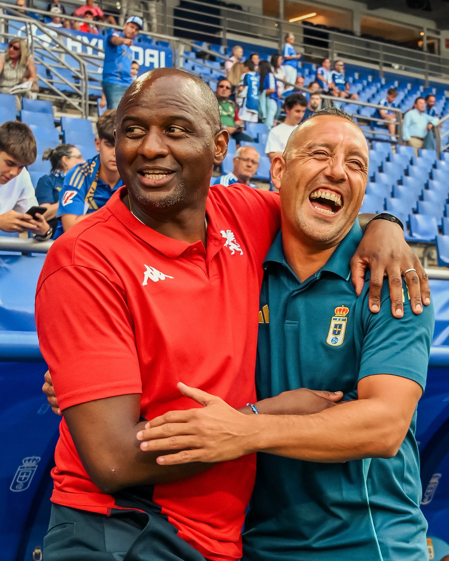 Patrick Vieira smiling and hugging former teammate Santi Cazorla at a stadium