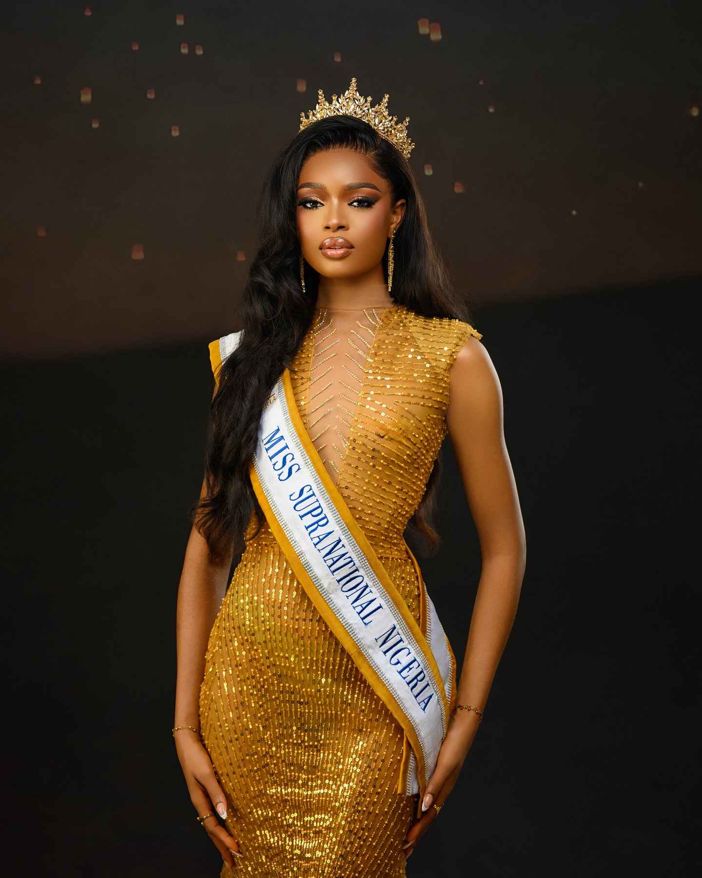 Gift Eno Ndah wearing a tiara, official sash, and gold sequined dress as Miss Supranational Nigeria 2026.