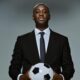 Slovan Bratislava head coach Yaya Touré holding a soccer ball in both hands.