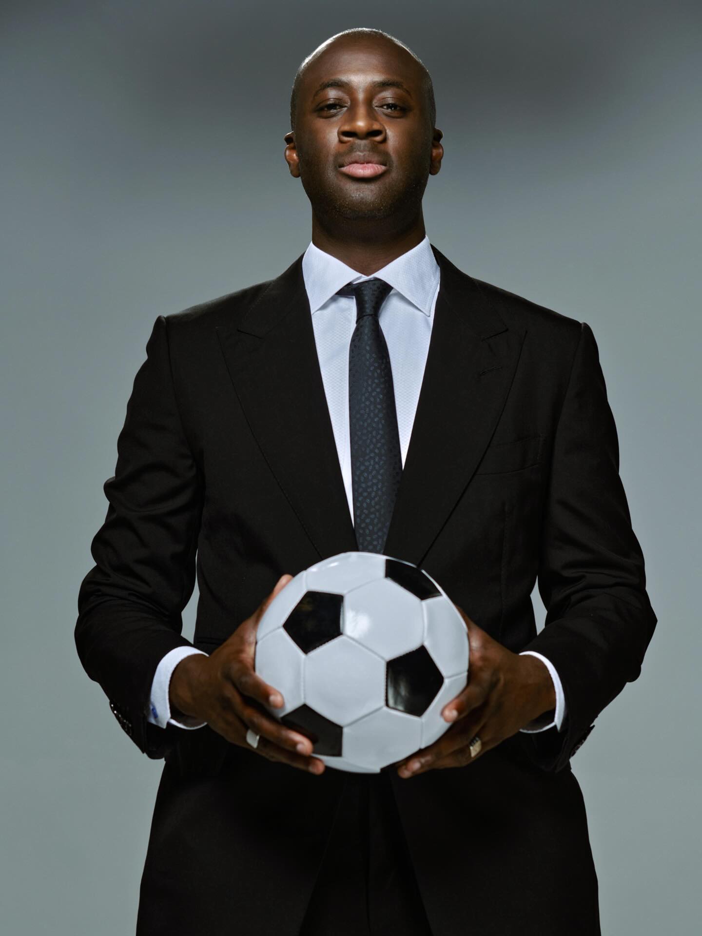 Slovan Bratislava head coach Yaya Touré holding a soccer ball in both hands.