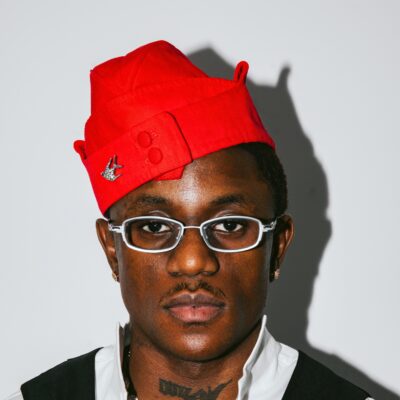 Nigerian singer Victony wearing glasses and a red cap in a portrait photo