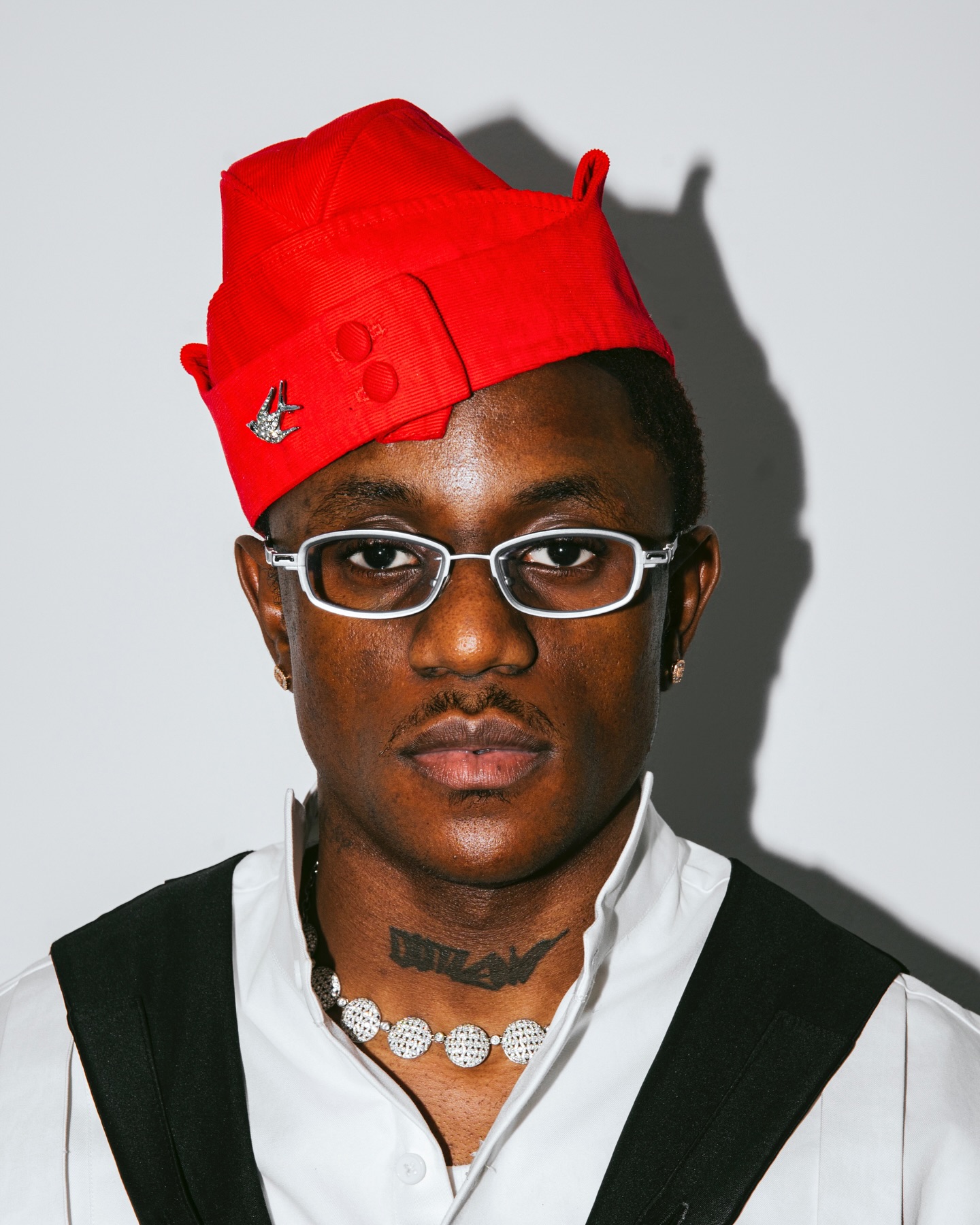 Nigerian singer Victony wearing glasses and a red cap in a portrait photo