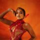 Uche Montana wearing a red and gold feathered Tubo dress at the 2026 AMVCA.
