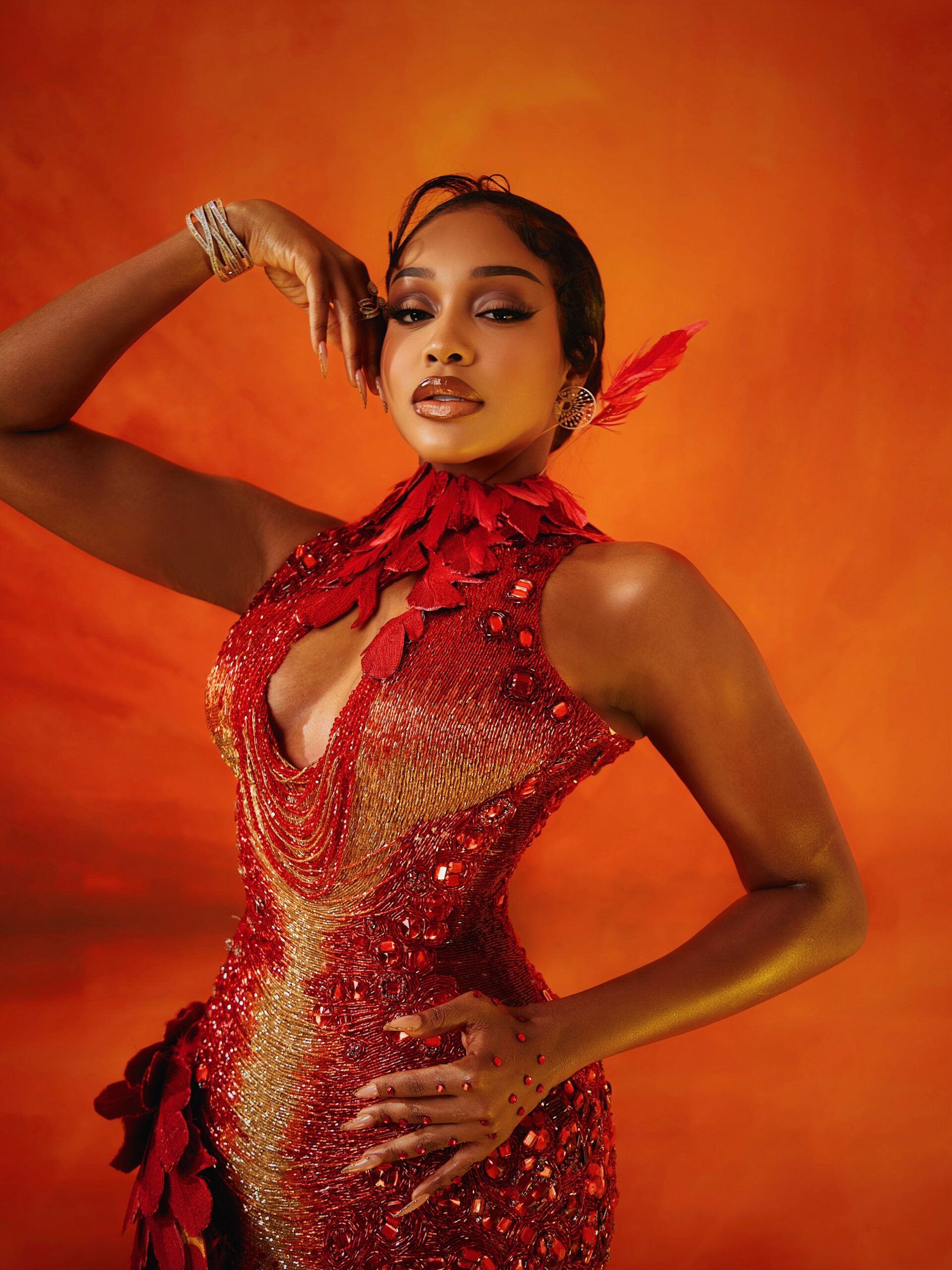 Uche Montana wearing a red and gold feathered Tubo dress at the 2026 AMVCA.