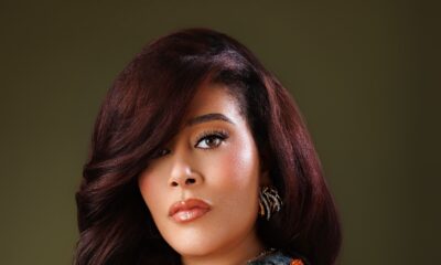 Adunni Ade wearing an orange-embellished patterned outfit with auburn styled hair.