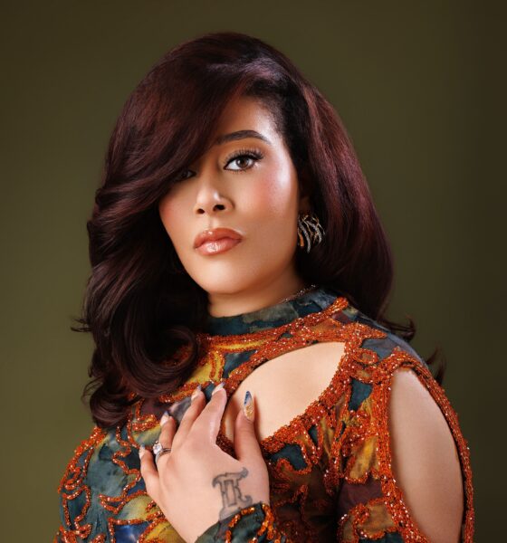 Adunni Ade wearing an orange-embellished patterned outfit with auburn styled hair.