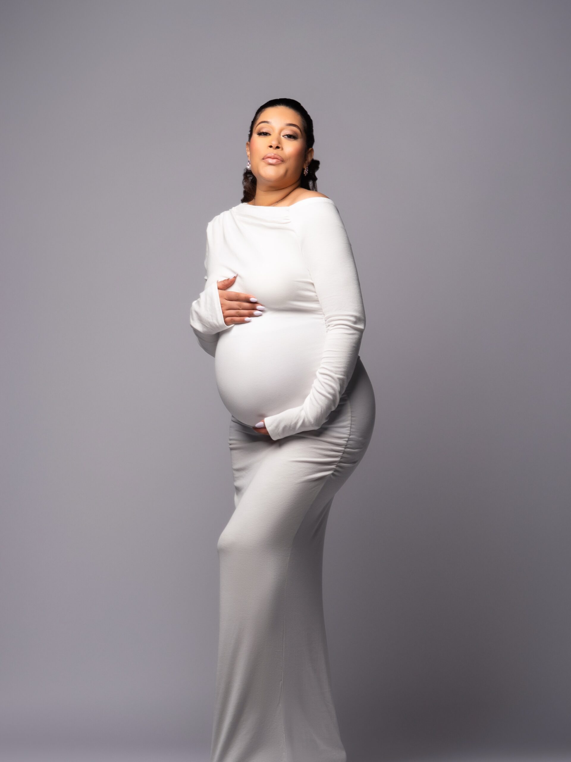 Adunni Ade wearing a long white fitted dress while pregnant with her daughter Baby Sal.