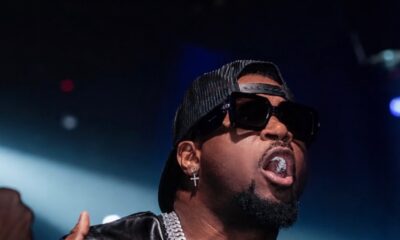 Nigerian Afrobeats musician Mr P wearing a black backward cap, dark sunglasses, silver Cuban link chains, and diamond earrings.