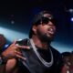 Nigerian Afrobeats musician Mr P wearing a black backward cap, dark sunglasses, silver Cuban link chains, and diamond earrings.