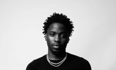 Nigerian singer Kunmie wearing a black t-shirt and silver chains in a monochrome portrait shot.