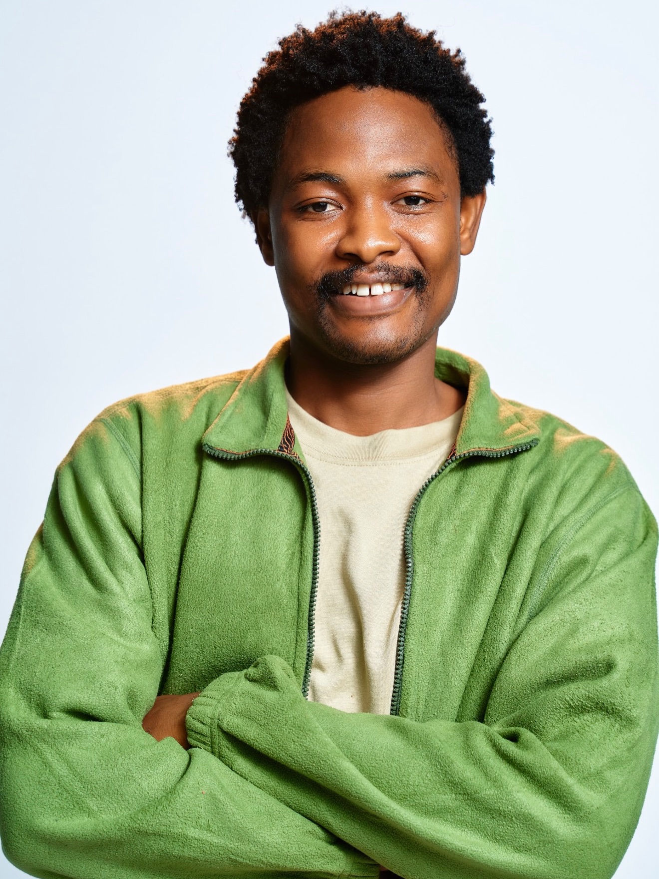 BBNaija Season 11 housemate Aikou wearing a green zip-up jacket with arms crossed.