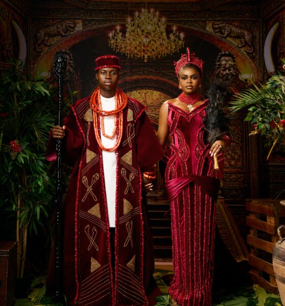 Peller and Jarvis posing in matching burgundy velvet traditional Edo wedding attire with coral beads and black ceremonial staff.