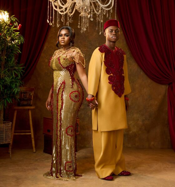 Peller and Jarvis holding hands in matching gold and burgundy custom traditional wedding outfits.