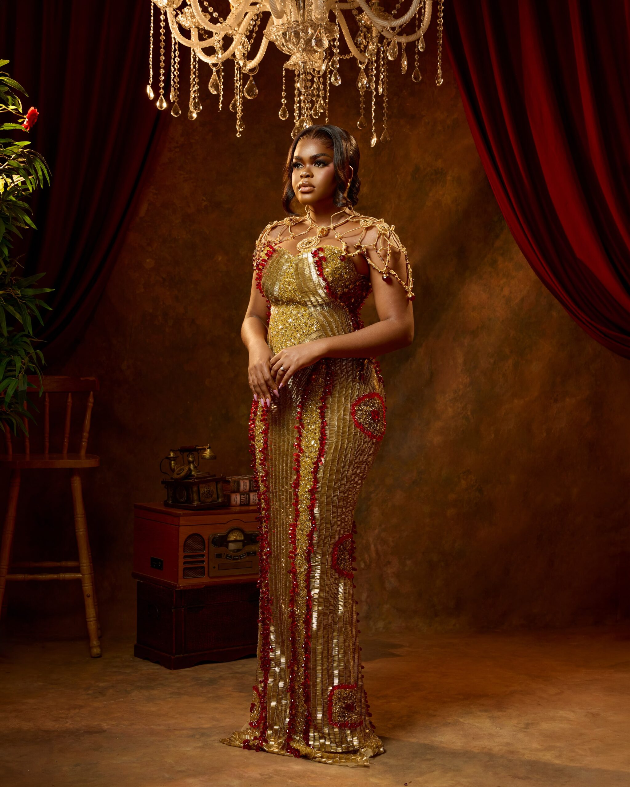 Jarvis posing in a gold corseted gown with crimson beaded embroidery and gold body jewellery.