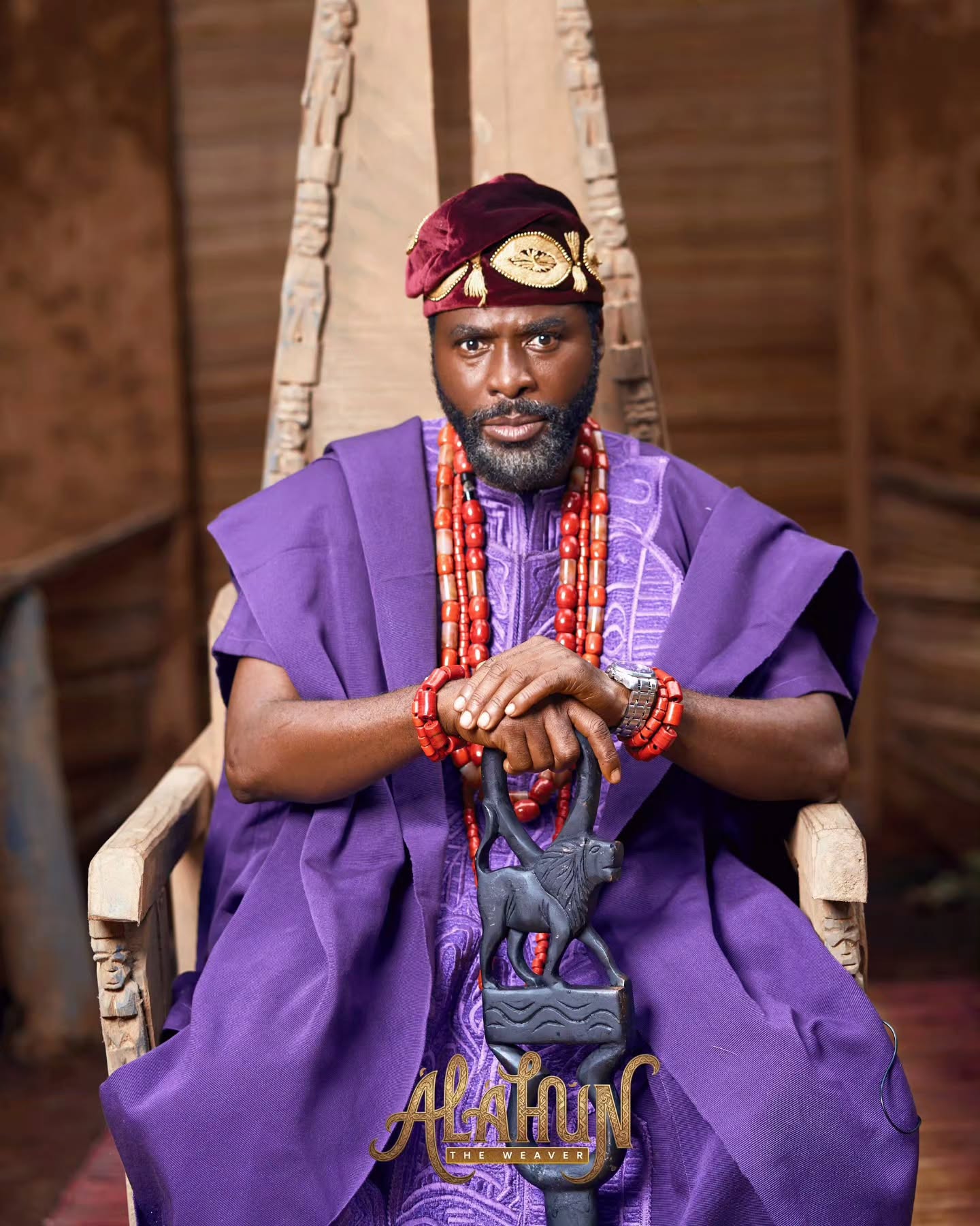Ibrahim Chatta seated on a carved wooden throne wearing purple Agbada regalia and coral beads for Alahun The Weaver.