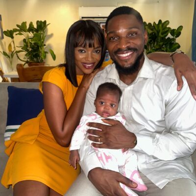 Tobi Bakre and Onyinye Odokoro smiling on a sofa while holding a baby on set of Before We Fall Asleep.