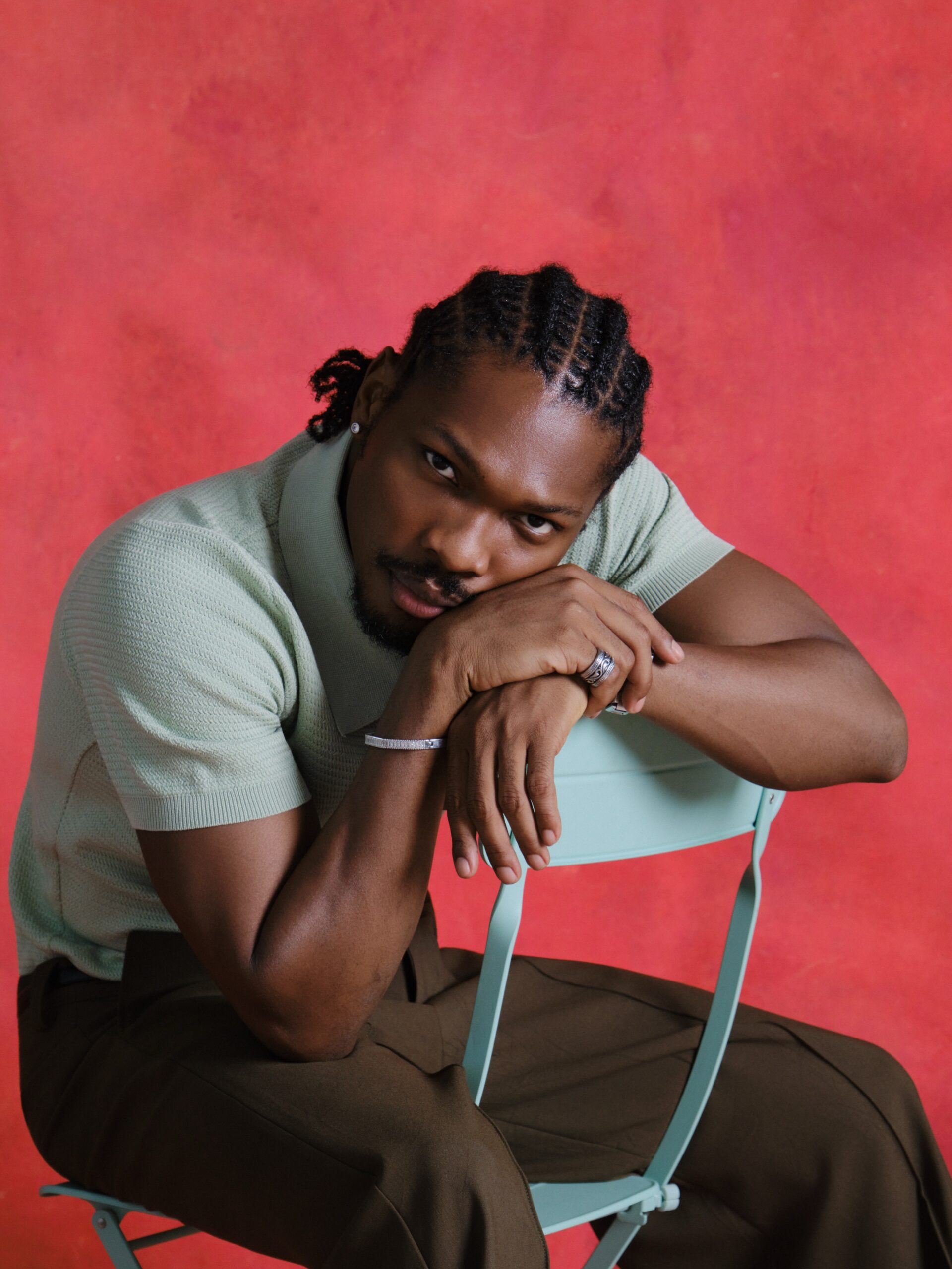 Mike Afolarin wearing a mint green micro-waffle knit polo shirt accessorised with a silver bracelet and silver rings.