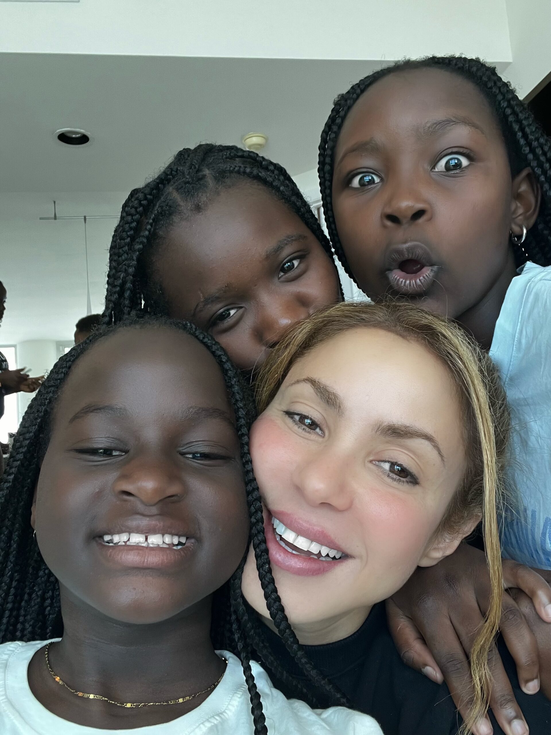 Shakira smiling in a group selfie with three young female members of the Triplets Ghetto Kids troupe.