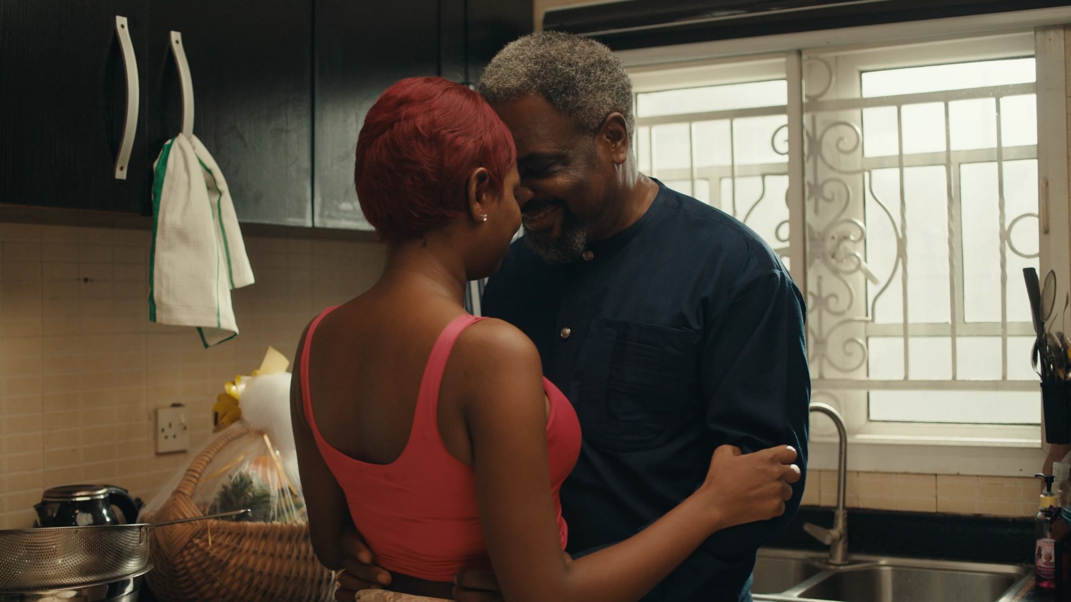 Film still from Dika Ofoma's A Happy Ending featuring male and female leads embracing in a kitchen.