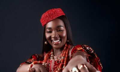 Big Brother Naija Season 11 housemate Goddessa smiling in a red beaded corset dress with traditional coral beads and a crown.