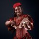 Big Brother Naija Season 11 housemate Goddessa smiling in a red beaded corset dress with traditional coral beads and a crown.