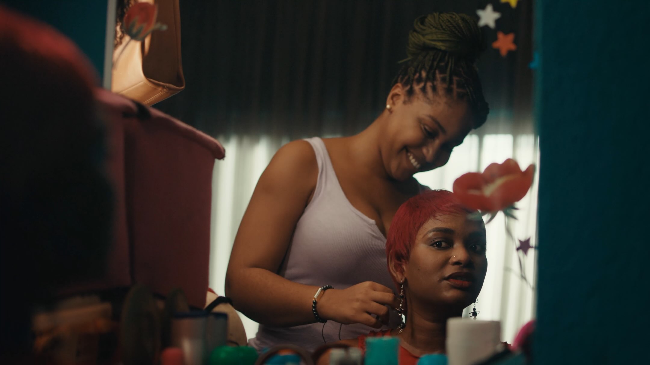 Film still from Dika Ofoma's A Happy Ending showing two women preparing in front of a mirror.