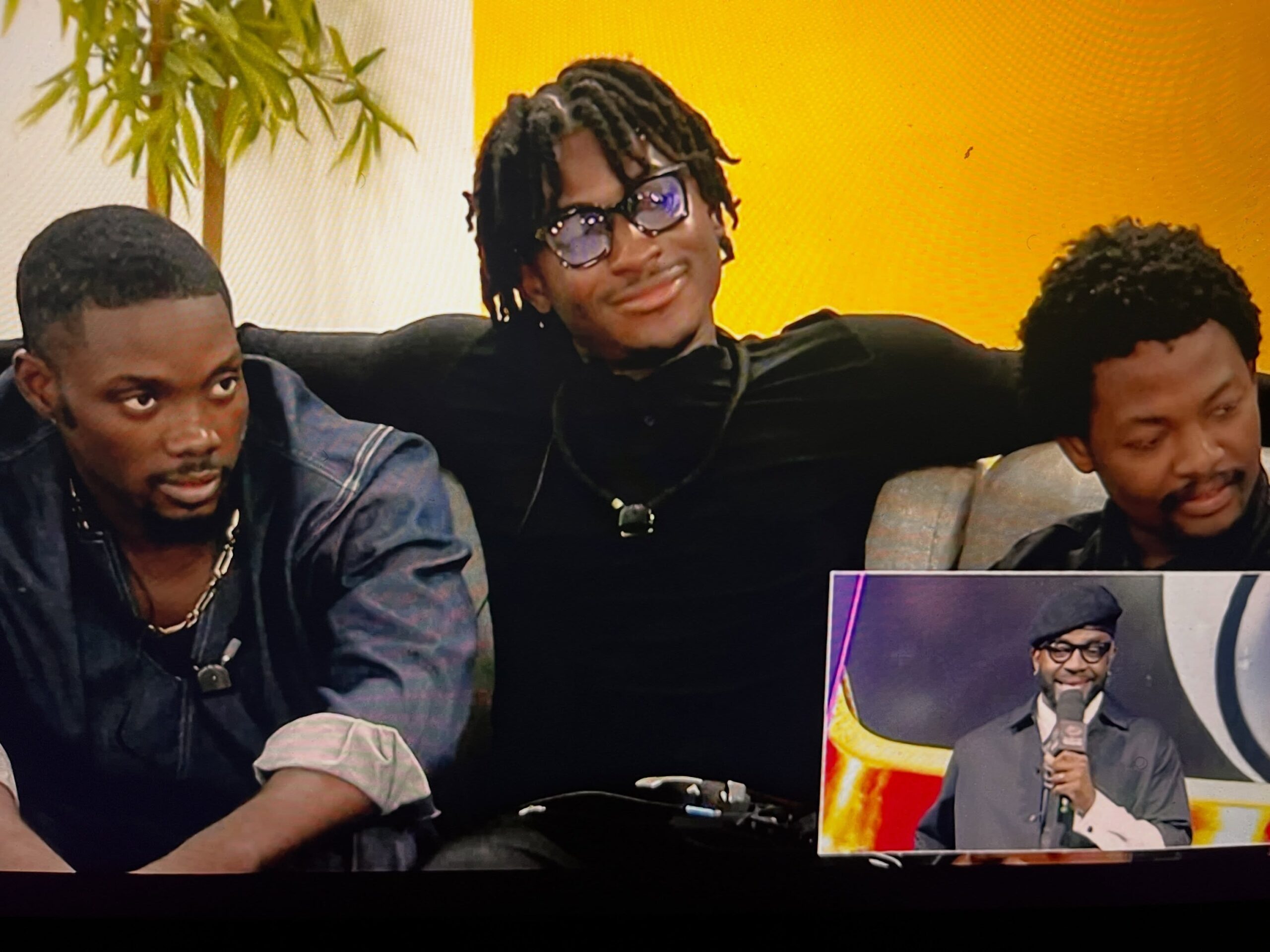 Three male Big Brother Naija Season 11 housemates sitting on a couch listening during the Sunday live eviction show.