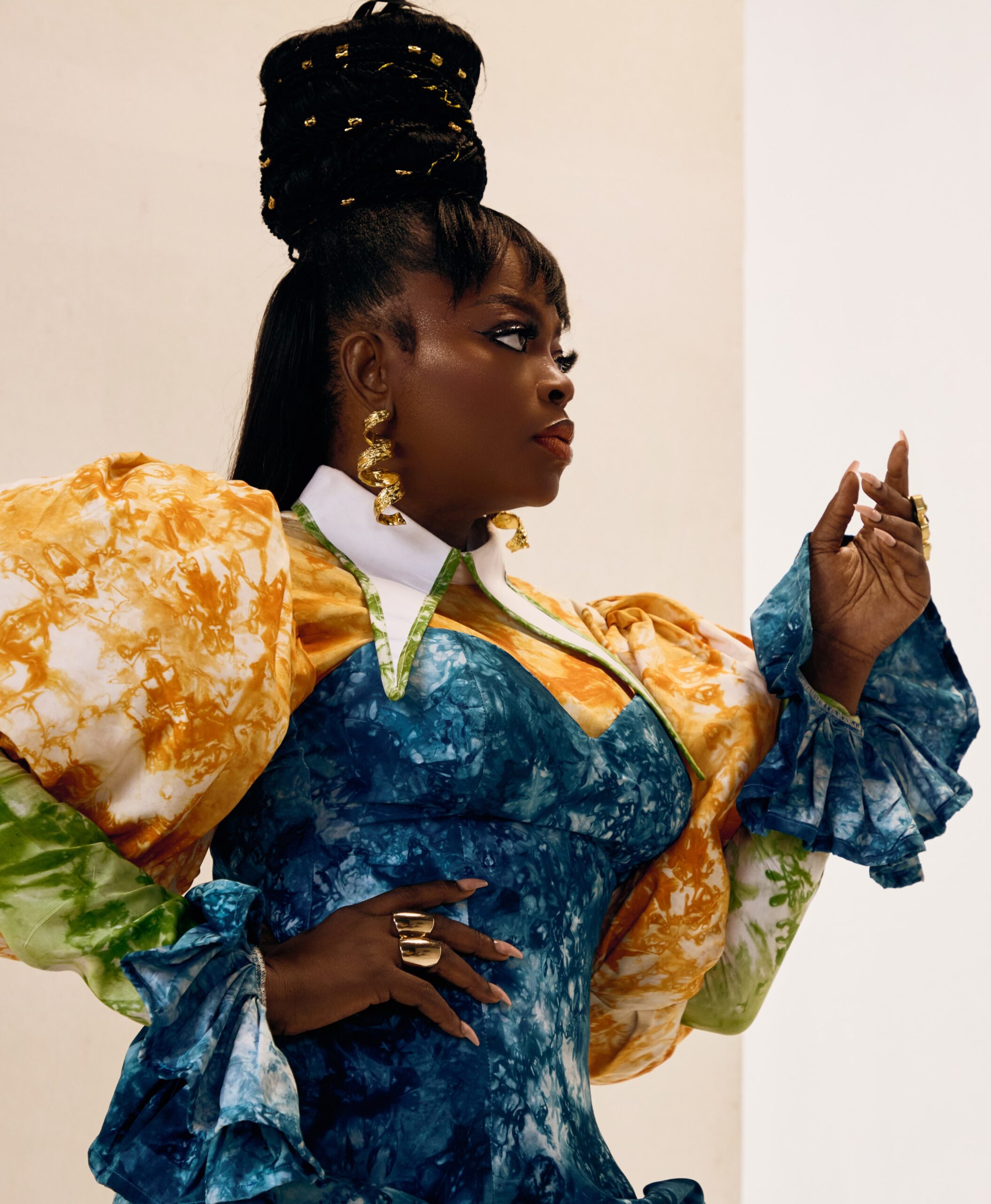 Funke Akindele wearing a blue and yellow puff-sleeve top with a high braided hair design.