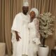 Simi and Adekunle Gold posing together in matching white traditional Yoruba outfits for their son Adeifemi's dedication.