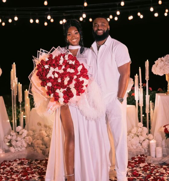 Meraiah Ekeinde in a white high-slit dress holding a red and white rose bouquet standing beside her fiancé Manny in all-white