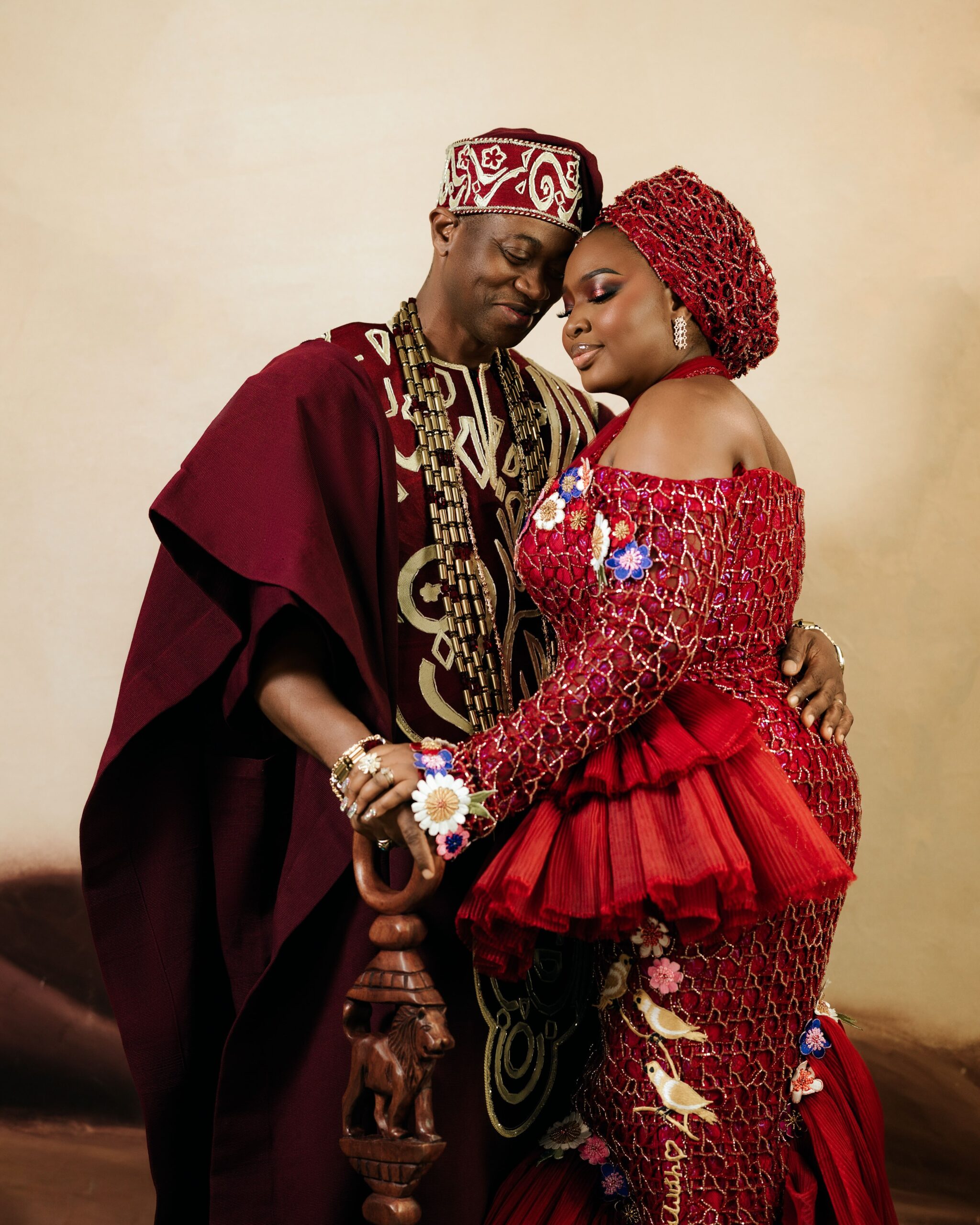 Lateef Adedimeji and Mo Bimpe embracing tenderly in matching burgundy traditional outfits for their triplets' thanksgiving party.