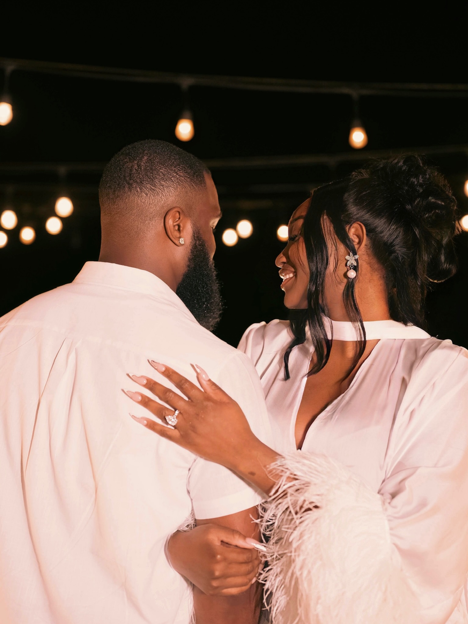 Meraiah Ekeinde's hand resting on Manny's shoulder displaying a large solitaire engagement ring