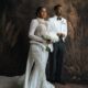 Peller and Jarvis posing together in their white wedding outfits.