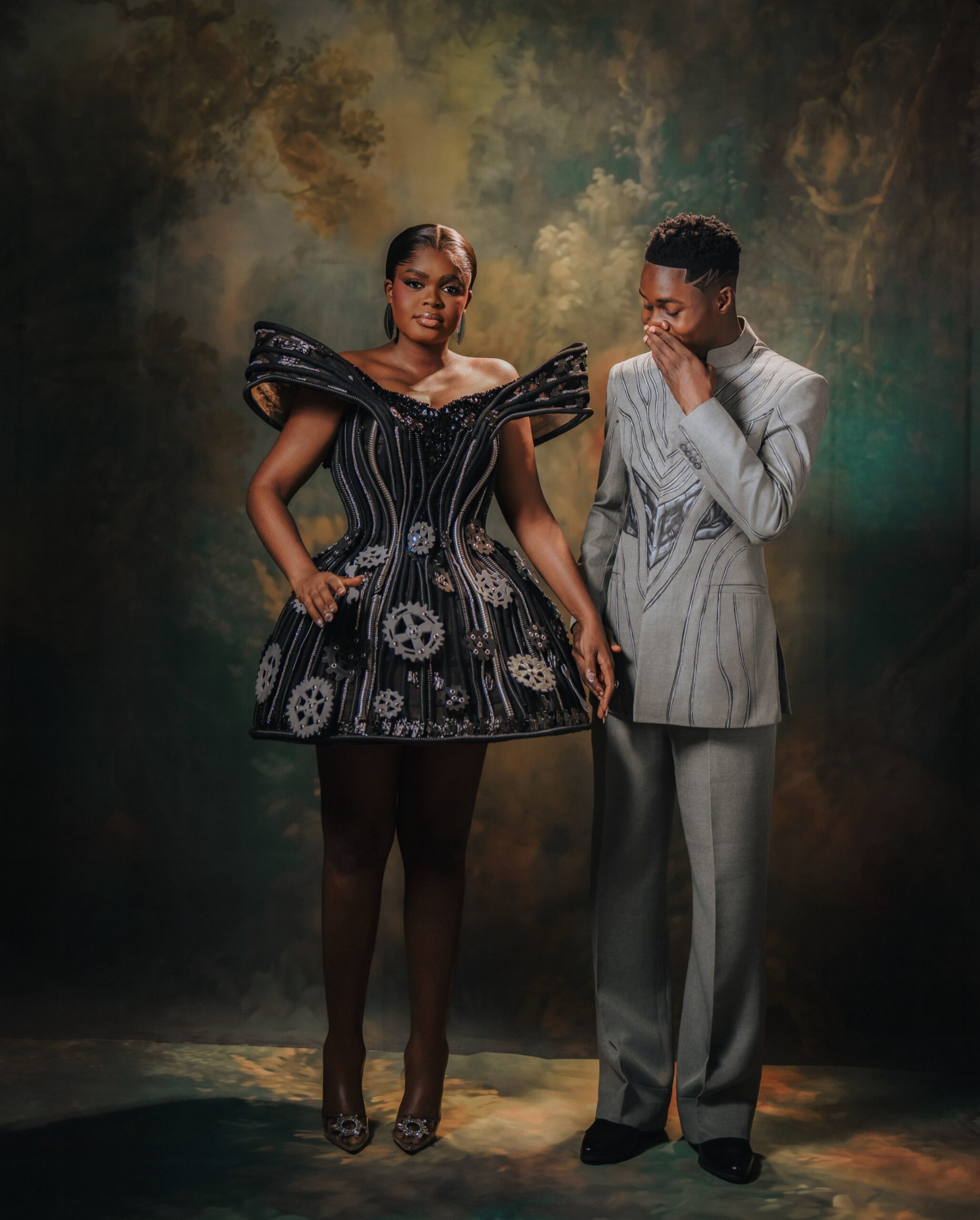Jarvis standing in her sci-fi inspired reception dress holding hands with Peller in his high-collar grey suit.