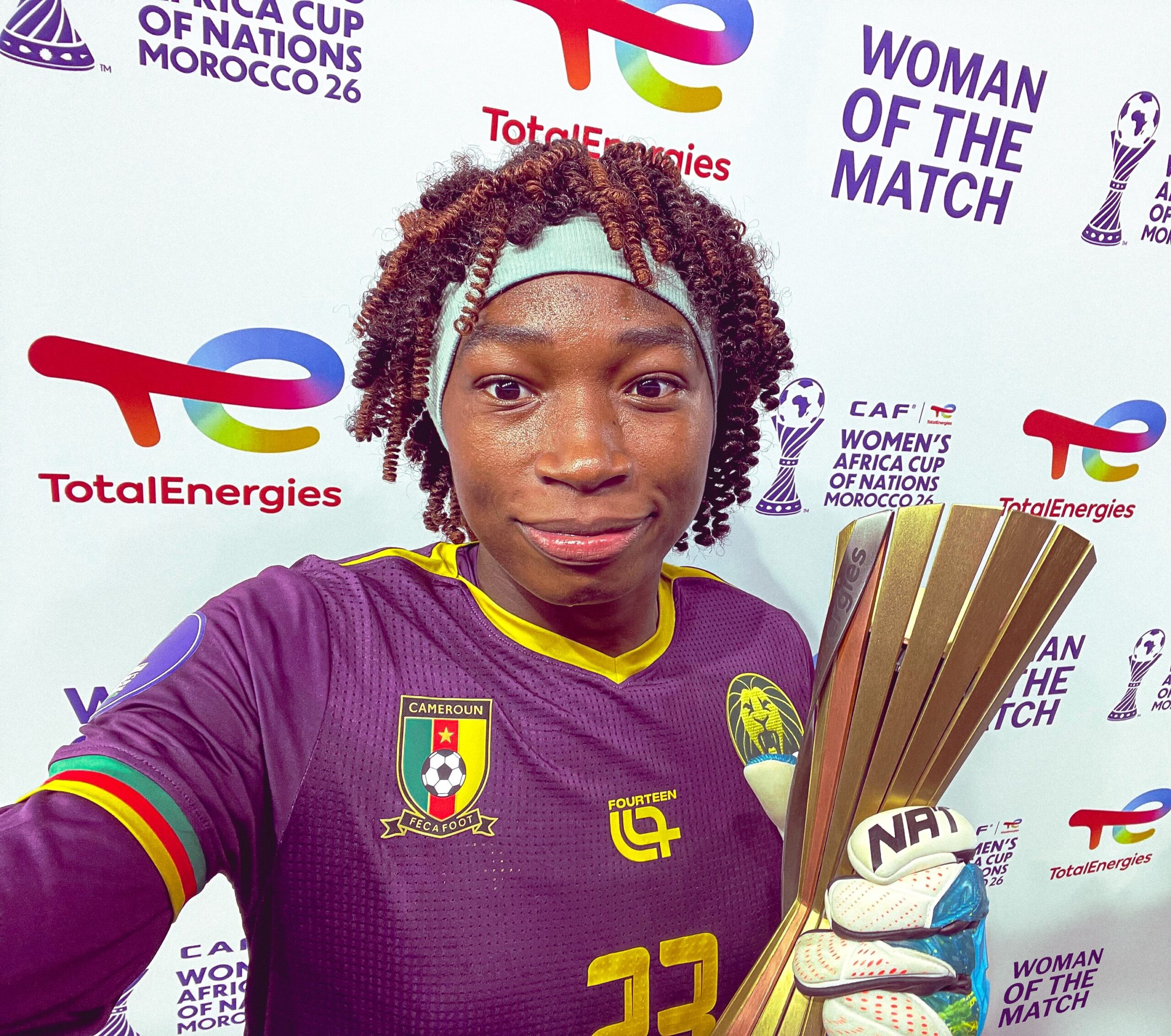 Michaely Bihina posing for a selfie holding her second TotalEnergies Woman of the Match award after saving four penalties against Morocco.
