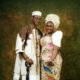 Close-up portrait of Lateef Adedimeji and Mo Bimpe smiling together in traditional Nigerian cream and gold outfits.